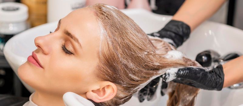 Beautiful young caucasian woman receiving wash her hair in a hair salon