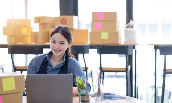 Portrait of Starting small businesses SME owners, Asian woman check online orders Selling products online and working with boxs freelance work at home Asian sme business online small medium enterprise.