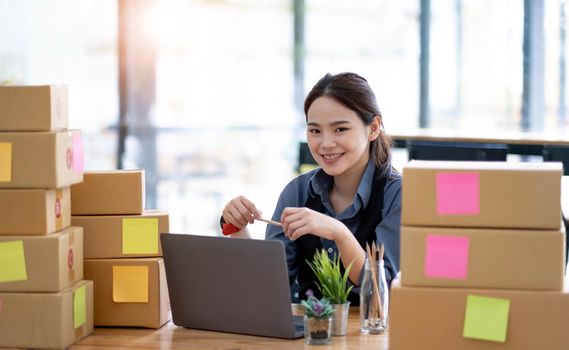 Portrait of Starting small businesses SME owners female entrepreneurs working on receipt box and check online orders to prepare to pack the boxes, sell to customers, sme business ideas online..