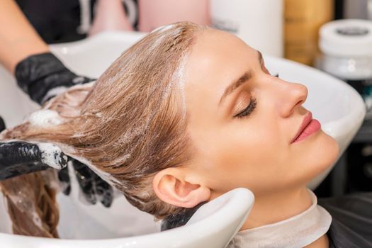 Beautiful young caucasian woman receiving wash her hair in a hair salon