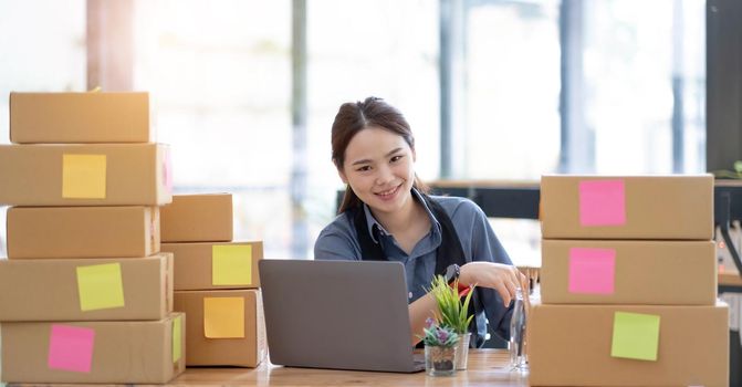 Portrait of Starting small businesses SME owners, Asian woman check online orders Selling products online and working with boxs freelance work at home Asian sme business online small medium enterprise.