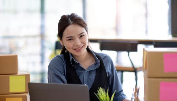 Portrait of Starting small businesses SME owners, Asian woman check online orders Selling products online and working with boxs freelance work at home Asian sme business online small medium enterprise.