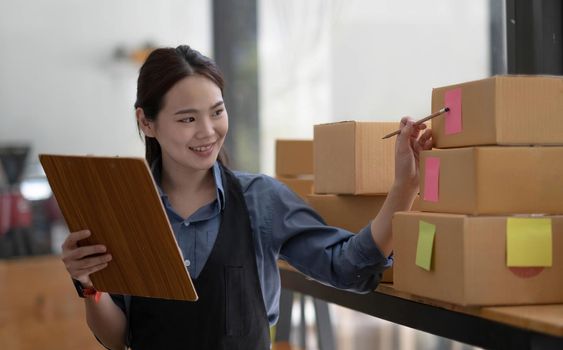Portrait of Starting small businesses SME owners female entrepreneurs working, box and check online orders to prepare to pack the boxes, sell to customers, sme business ideas online..