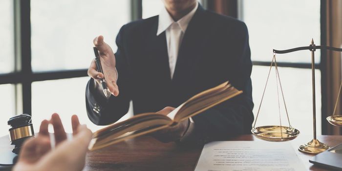 Business woman and lawyers discussing contract papers with brass scale on wooden desk in office. Law, legal services, advice, Justice concept.