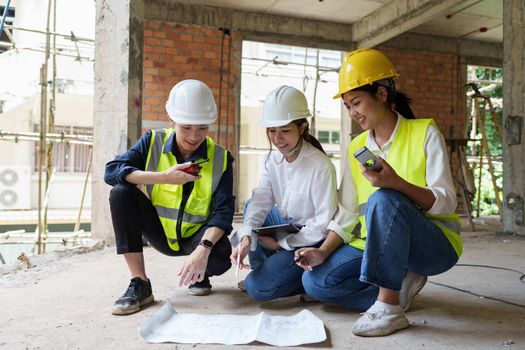 Structural engineer and architect discussing and working with blueprints at the outdoors construction site.