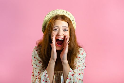 Woman with red hair very glad, she screaming loud. Woman trying to get attention. Concept of sales, profitable offer. Excited happy lady on pink studio background. High quality photo