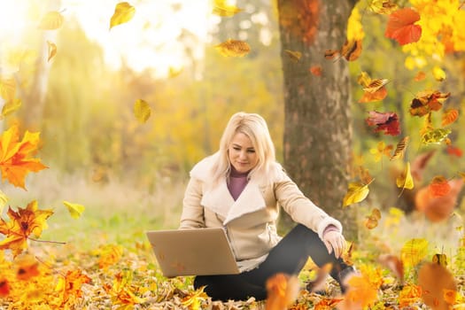 Beautiful girl walking outdoors in autumn. Smiling girl collects yellow leaves in autumn. Young woman enjoying autumn weather. High quality photo