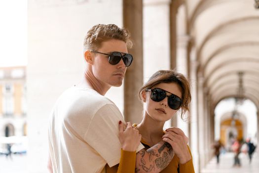 Young beautiful hipster couple in love walking on old city street, summer Europe vacation, travel, fun, happy, smiling, sunglasses, trendy outfit, romance, date, embracing