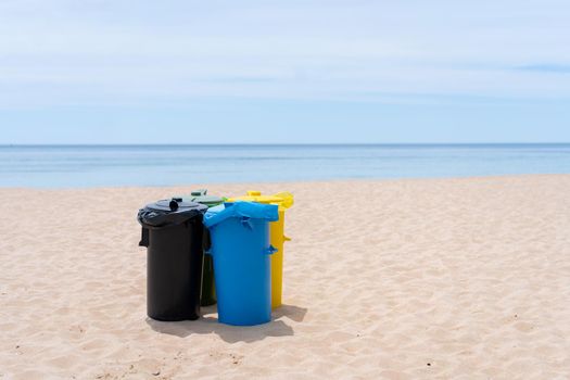 Clean beach garbage bins. Multi colored garbage containers for separate collection of garbage stand on empty beaches near the ocean