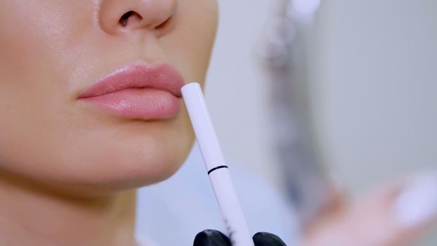 clinic, a beauty salon, a large plan of the lips, the doctor shows the patient a lip zone for injection of hyaluronic acid, discuss the procedure of lip augmentation. High quality photo