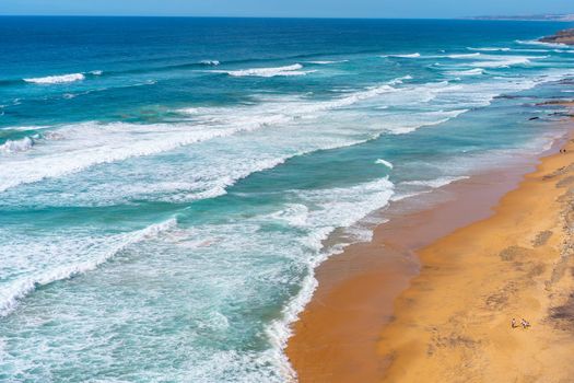 Aerial view of tropical sandy beach and ocean with turquoise water with waves. Sunny day on Atlantic ocean beach in Portugal
