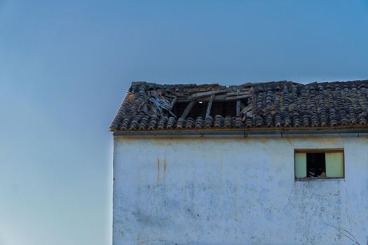 abandoned house with sunken roof and blue sky in the background