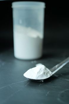 Washing powder in plastic spoon on black background ,