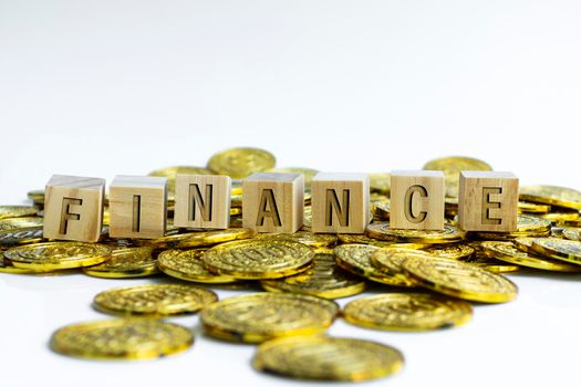 Finance text on wood block with a pile of gold coins on white background. Business concept.