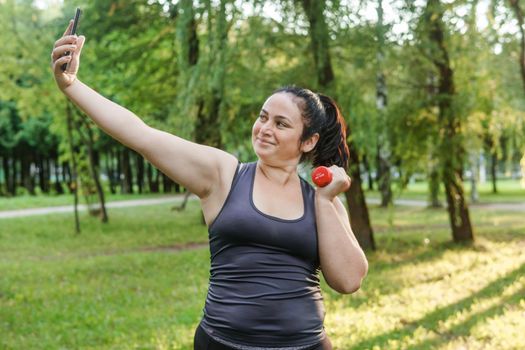 A charming brunette woman plus-size body positive practices sports in nature.