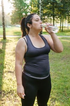 A charming brunette woman plus-size body positive practices sports in nature.