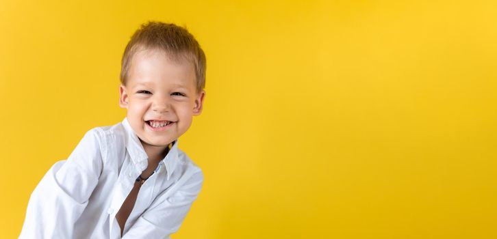 Banner Funny Preschool Child Boy in unbuttoned shirt smile narrow eye on Yellow Background Copy Space. Happy Smiling Kid Go Back to School, Kindergarten. Success, Motivation, Genius, Superhero concept.