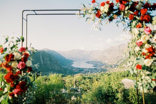 View of the Kotor Bay surrounded by a ring of mountains through a wedding arch with flowers. High quality photo