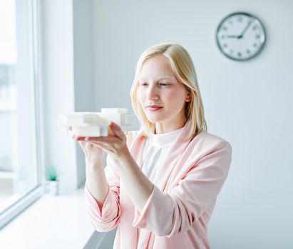 portrait of a young business woman holding a modern house model in the office