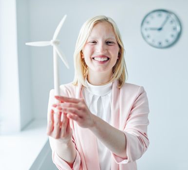 portrait of a young business woman holding a windmill model in the office