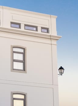White building at sunset against a blue sky with a vintage lantern background