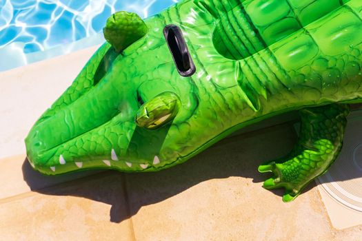 Inflatable crocodile on the side of the pool on a sunny day close up
