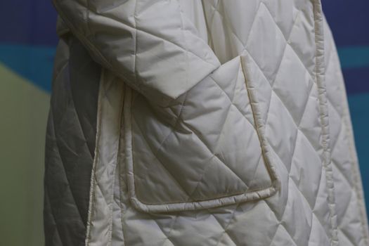 Close-up of white waterproof clothing material. Sleeve and pocket of a winter white coat close-up.