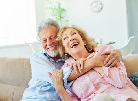 Portrait of a happy senior couple embracing hugging and having fun at home
