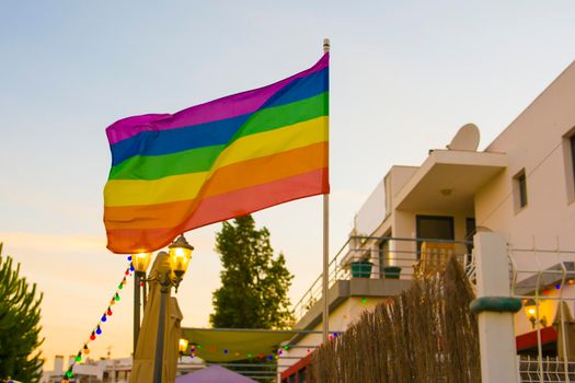 Flag lgbt against the backdrop of the setting sun in an open-air bar