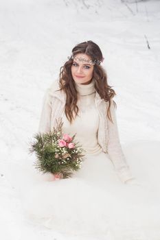 Beautiful bride in a white dress with a bouquet in a snow-covered winter forest. Portrait of the bride in nature.Beautiful bride in a white dress with a bouquet in a snow-covered winter forest. Portrait of the bride in nature.