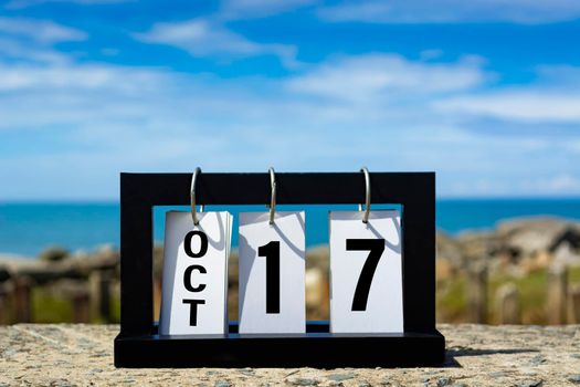 Oct 17 calendar date text on wooden frame with blurred background of ocean. Calendar date concept.