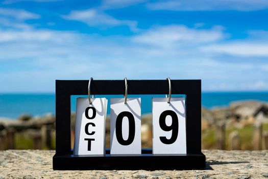 Oct 09 calendar date text on wooden frame with blurred background of ocean. Calendar date concept.