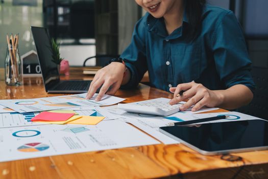 businesswoman working on desk office with using a calculator to calculate the numbers, finance accounting concept.