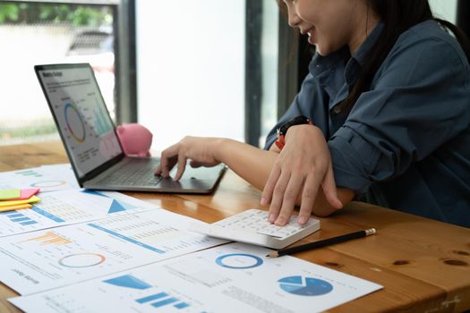 businesswoman working on desk office with using a calculator to calculate the numbers, finance accounting concept.