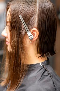 Close up side view of young brunette caucasian woman with split hair in sections in a hair salon