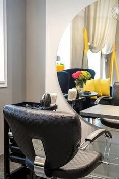 Interior of a beauty salon. Black leather chair in front of the mirror in the beauty salon. Interior of a beauty salon