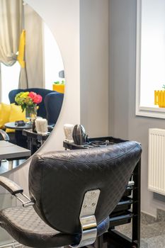 Interior of a beauty salon. Black leather chair in front of the mirror in the beauty salon. Interior of a beauty salon