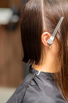 Close up side view of young brunette caucasian woman with split hair in sections in a hair salon