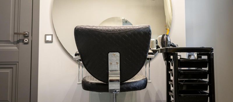 Interior of a beauty salon. Black leather chair in front of the mirror in the beauty salon. Interior of a beauty salon