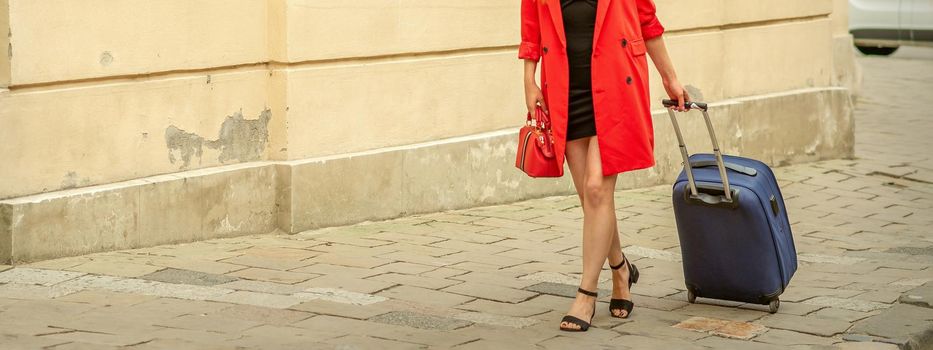 A beautiful young caucasian woman is walking with a suitcase on an old city street