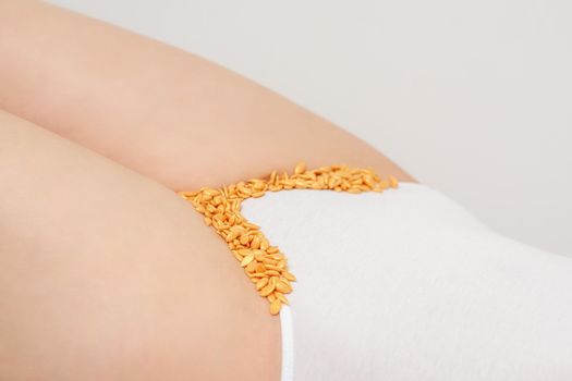 Depilation of the bikini area. Bikini zone of a young woman with wax hard beans lying down on a white background