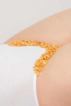 Depilation of the bikini area. Bikini zone of a young woman with wax hard beans lying down on a white background