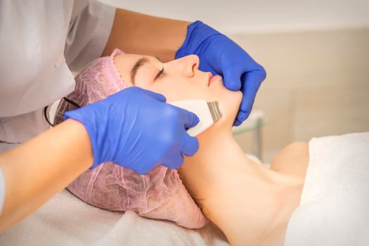 Beautiful young woman receiving ultrasonic cavitation facial cleansing in beauty spa salon