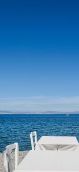 White restaurant tables on the beach in summer - travel, vacation and summer concept. The perfect lunch with a sea view