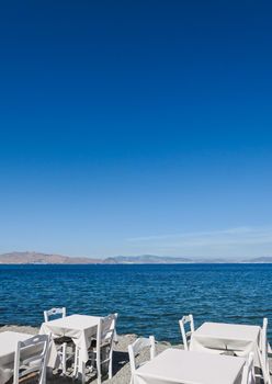 White restaurant tables on the beach in summer - travel, vacation and summer concept. The perfect lunch with a sea view