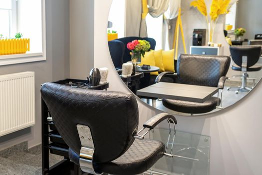 Interior of a beauty salon. Black leather chair in front of the mirror in the beauty salon. Interior of a beauty salon