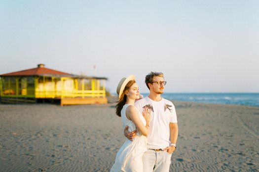 Man and woman stand hugging on the beach and look at the sea. High quality photo