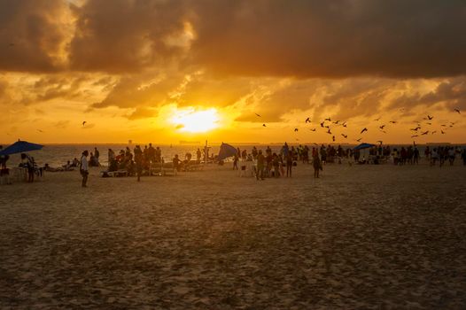 Silouette of people watching the sunset on the sea in the beach of Isla Mujeres in Mexico