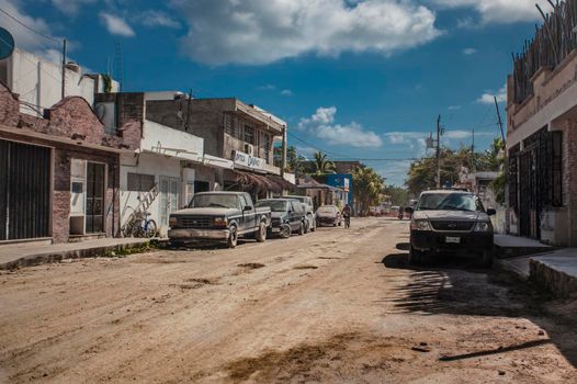 Tulum, Mexico 20 august 2022: View of a street of Tulum in Mexico with unpaved roads and some vehicles parked at the side.