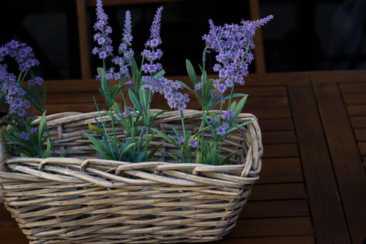 wicker basket with decorative lavender bouquet on a wooden table in the garden